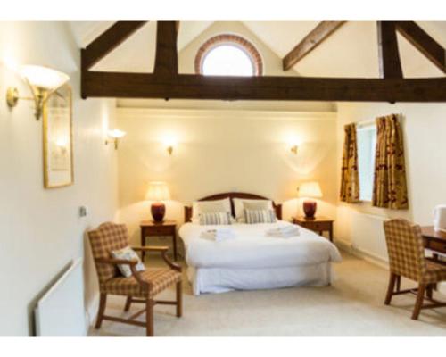 a bedroom with a large bed and two chairs at The Bull Inn in Bourne