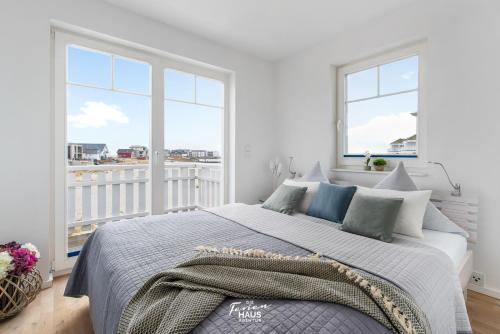 a bedroom with a large bed and two windows at Strandblick in Olpenitz