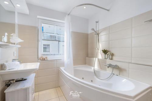 a white bathroom with a tub and a sink at Strandblick in Olpenitz