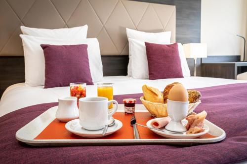 a tray with breakfast foods and drinks on a bed at Les Jardins de St Cloud in Saint-Cloud