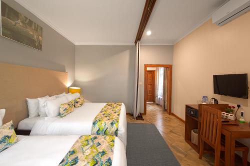 a hotel room with two beds and a desk and a television at Airport Planet Lodge in Kingori
