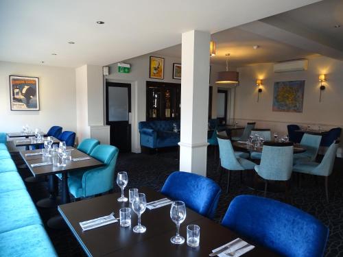 a dining room with tables and blue chairs at The Beeches Hotel & Leisure Club in Nottingham