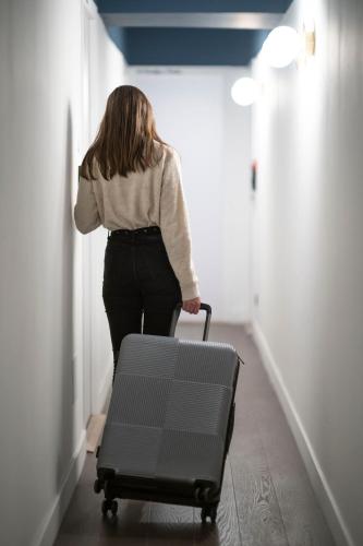 a woman walking down a hallway with a suitcase at Monsieur Miot Concept Hotel - Bastia centre in Bastia