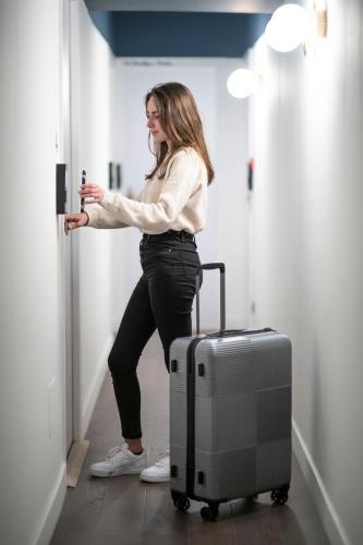 a woman standing in a hallway with a suitcase at Monsieur Miot Concept Hotel - Bastia centre in Bastia