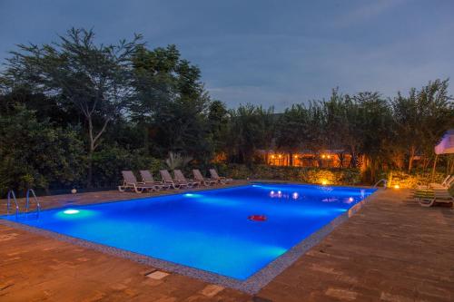 a swimming pool with blue water at night at Airport Planet Lodge in Kingori