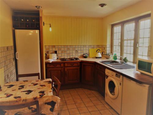a kitchen with a refrigerator and a sink and a table at Iffin Farmhouse in Canterbury