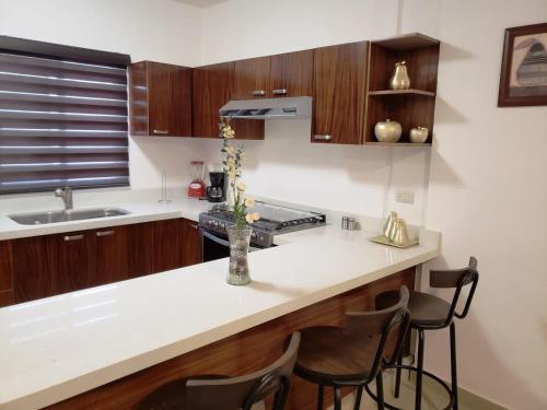 une cuisine avec un comptoir blanc et des placards en bois dans l'établissement Casa con Alberca a solo 5 minutos de Playas de Nuevo Vallarta RBL33, à Nuevo Vallarta