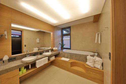 uma casa de banho com 2 lavatórios, uma banheira e um espelho. em Mawell Resort em Langenburg