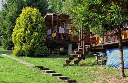 波蘭茲克的住宿－Domki Pod Wzgórzem，树旁的一座有楼梯的建筑