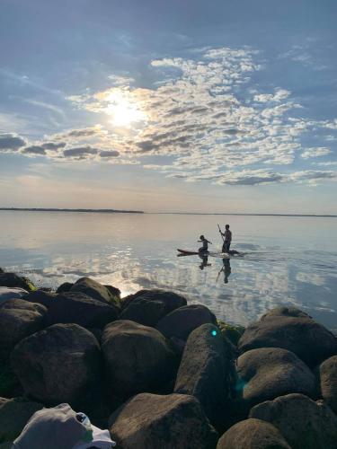 two people are standing on paddle boards in the water at On the beach Apartment in Brenderup
