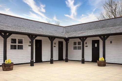 a white garage with black doors and a roof at The Ferry Boat Inn in North Fambridge