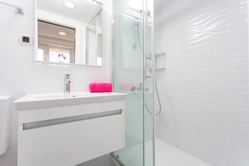 een witte badkamer met een wastafel en een douche bij Villa King Apartments in Brela