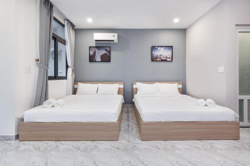 two beds in a room with white sheets at YOURS studio airport in Ho Chi Minh City