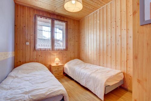 twee bedden in een kamer met houten wanden en een raam bij LES SERMES 1 in Morzine