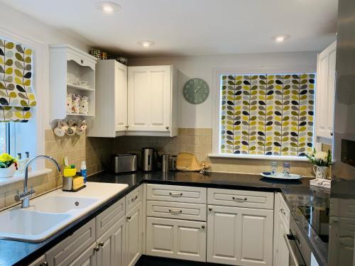 uma cozinha com armários brancos, um lavatório e uma janela em Shepherds House em Swanage
