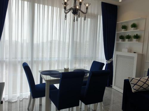 a dining room with a glass table and blue chairs at Sunny Apartments near the sea on Genuezskaya in Odesa