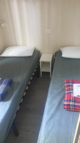 two twin beds in a room with a table at Camping Parc des 7 fonts in Agde