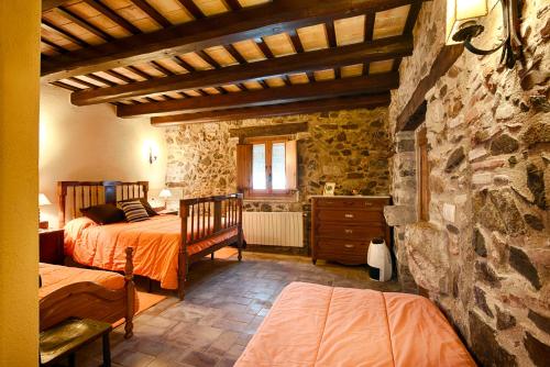 1 dormitorio con 2 camas y pared de piedra en Agroturisme Sant Dionis en Campllong