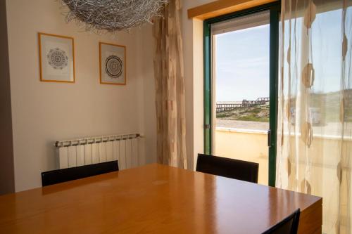 a dining room with a table and a large window at The Beach House in Figueira da Foz