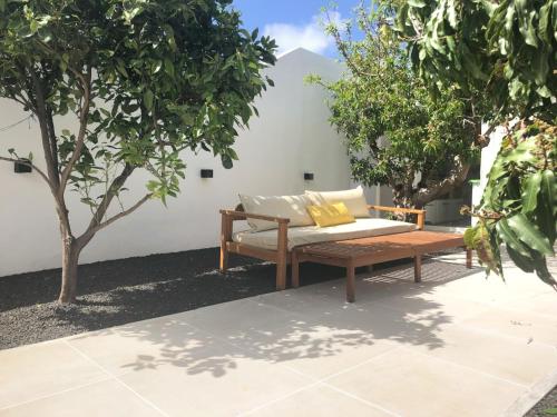 un banco de madera sentado en un patio con árboles en Casita blanca cerca de Timanfaya, en Tinguatón