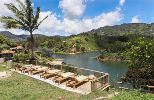 a group of lounge chairs and a river with mountains at Soy Local Guatape in Guatapé