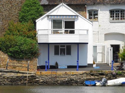 uma casa branca com um barco à frente em The Boathouse em Kingsbridge