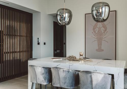 a dining room with a white table and silver chairs at THE WAVE GRANDE VILLA KATHISMA Lefkada in Lefkada Town