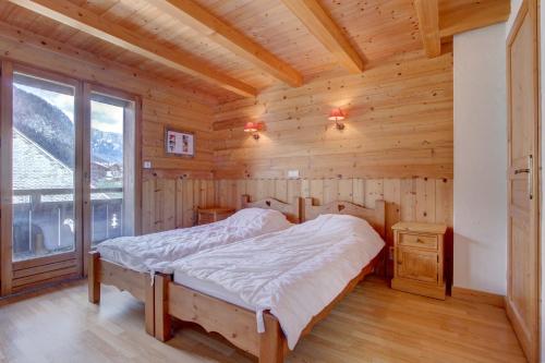 um quarto com uma cama num chalé de madeira em LES SERMES M504 em Morzine
