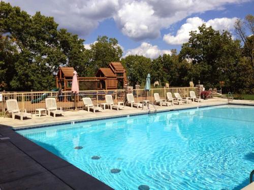 a large swimming pool with chairs and a house at Lodge 68 in Branson