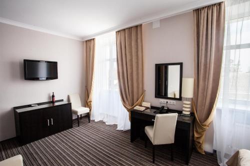 a hotel room with a desk and a television at Optima Sumy in Sumy