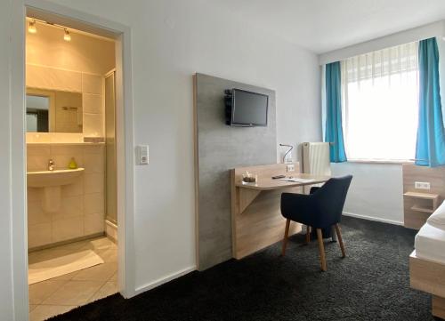 a hotel room with a desk and a bed at Hotel zur Sonne GmbH in Bodelshausen