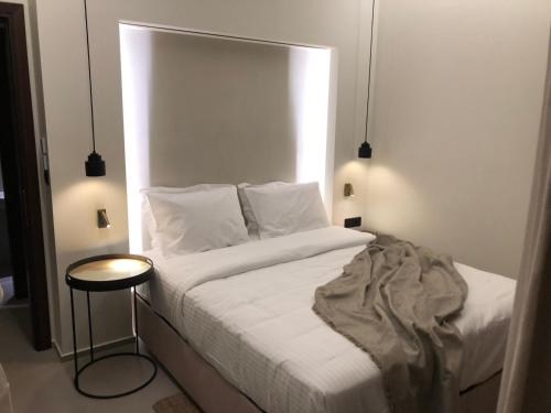 a bedroom with a white bed and a small table at THE WAVE GRANDE VILLA KATHISMA Lefkada in Lefkada Town