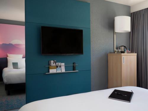 a hotel room with a blue wall with a tv at Mercure Annemasse Porte De Genève in Gaillard