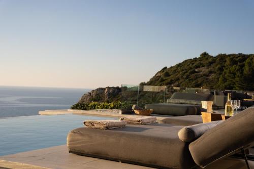 a pool with chairs and a view of the ocean at THE WAVE GRANDE VILLA KATHISMA Lefkada in Lefkada Town