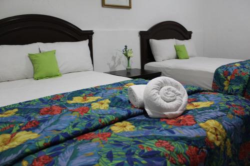 a hotel room with two beds with a towel on the bed at Hotel El Cid in Mérida
