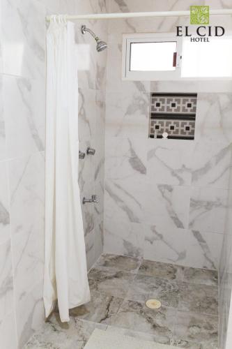 a shower with a white shower curtain in a bathroom at Hotel El Cid in Mérida