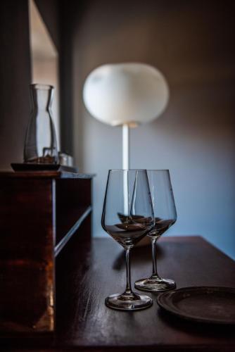 two wine glasses sitting on a table with a lamp at Boutique Hotel Al Palazzo Rosso in Neive