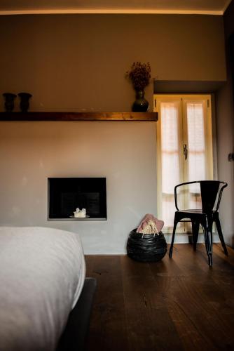 a bedroom with a bed and a chair and a fireplace at Boutique Hotel Al Palazzo Rosso in Neive