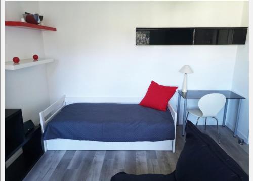 - une chambre avec un lit doté d'un oreiller rouge et d'un bureau dans l'établissement Logement entier Saint brieuc centre, à Saint-Brieuc