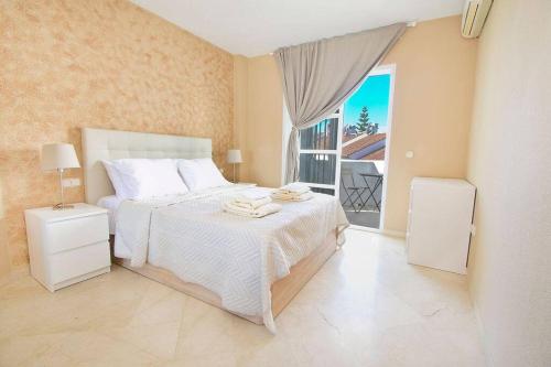 1 dormitorio con cama blanca y ventana en Spectacular Apartment in Matchroom Country Club, en Fuengirola