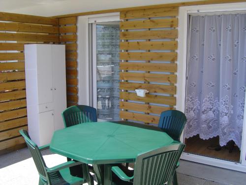 une table et des chaises vertes dans une chambre avec fenêtre dans l'établissement Terrasse sur le lac, à La Rochelle