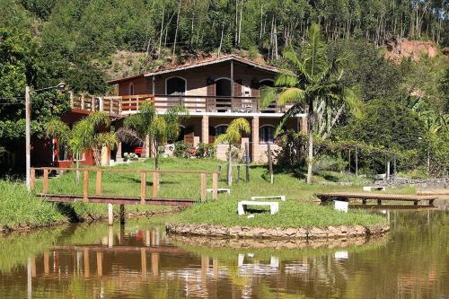 a house sitting on the side of a river at Chales em Salesopolis - Recanto da Barra in Salesópolis