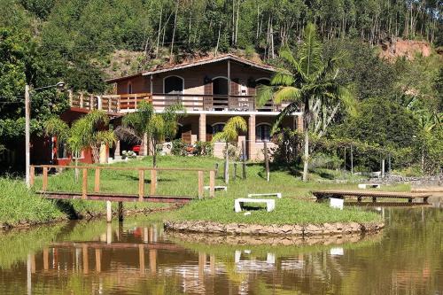 a house sitting on the side of a river at Chales em Salesopolis - Recanto da Barra in Salesópolis