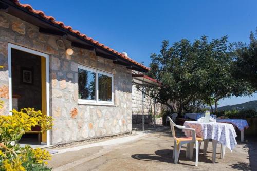 Guest House Simunovic في Suđurađ: طاولة وكراسي أمام منزل حجري