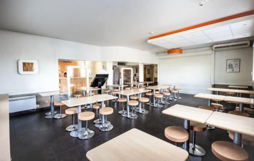 a room with tables and stools in a classroom at ibis budget Bordeaux Sud in Villenave-dʼOrnon