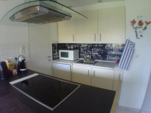 a kitchen with white cabinets and a sink and a microwave at Liège centre 6 rue montagne sainte Walburge, 4000 Liège, pour 2 pers à 3 minutes de la gare st Lambert in Liège