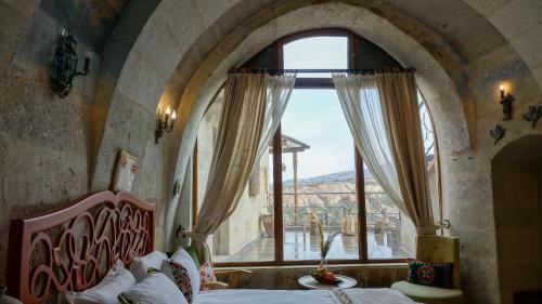 a bedroom with a bed and a large window at Pigeon Hotel Cappadocia in Uchisar