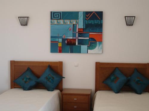 two beds in a room with a painting on the wall at Apartamentos Atlantico by OA in Albufeira