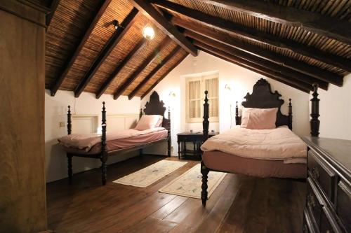 two beds in a room with wooden floors and ceilings at Casa Ocre in Vila Nova de Milfontes