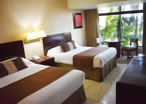 a hotel room with two beds and a window at Hotel San Luis Lindavista in Culiacán